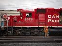 Des employés de CP Rail passent devant des locomotives dans les triages Alyth à Calgary.