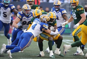 Le secondeur des Blue Bombers de Winnipeg, Adam Bighill, affronte le secondeur des Elks d'Edmonton, Kevin Brown, lors du premier quart d'action de la LCF à Winnipeg, jeudi.