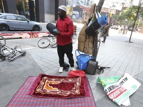 Asuman Najib Ssali, d'Ouganda, avec tous ses biens matériels suspendus à un arbre, fait partie des nombreux réfugiés qui dorment dans la rue à l'extérieur du refuge de la ville de Toronto sur la rue Peter alors qu'ils attendent un logement le vendredi 14 juillet 2023 .