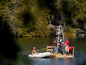 Tim Patterson, professeur de géologie à l'Université Carleton (R) dirige une équipe de scientifiques qui récupèrent une sonde au fond du lac Crawford tout en recueillant des échantillons de couches de sédiments au lac Crawford près de Milton, Ontario, Canada, le 12 avril 2023.