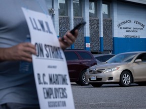 Un travailleur du Syndicat international des débardeurs et des entrepôts fait du piquetage devant le centre de répartition de la BC Maritime Employers Association après un préavis de grève de 72 heures et aucune entente conclue à la table de négociation à Vancouver, le samedi 1er juillet 2023.