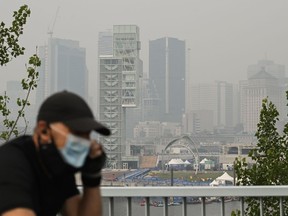 Un homme porte un masque facial alors qu'il parcourt à vélo la ligne d'horizon de Montréal, le dimanche 25 juin 2023.