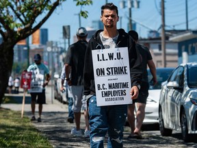 Des travailleurs portuaires en grève appartenant à l'International Longshore and Warehouse Union Canada marchent sur la ligne de piquetage près de l'entrée du port de Vancouver à Vancouver.