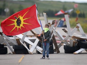 Un jeune enfant porte un drapeau à un barrage routier à Brady Road Landfill le mardi 11 juillet 2023, dans le cadre d'une manifestation contre la décision de la première ministre du Manitoba, Heather Stefanson, de ne pas rechercher les victimes de meurtre.