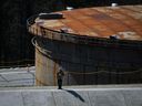 Un travailleur se tient debout sur une berme en béton au projet d'agrandissement du pipeline Trans Mountain au parc de stockage du terminal de Burnaby à Burnaby, en Colombie-Britannique, en mars. 