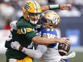 Le quart-arrière des Elks d'Edmonton Taylor Cornelius est plaqué par Brandon Alexander des Blue Bombers de Winnipeg lors de la première mi-temps de la LCF à Winnipeg le 20 juillet 2023.