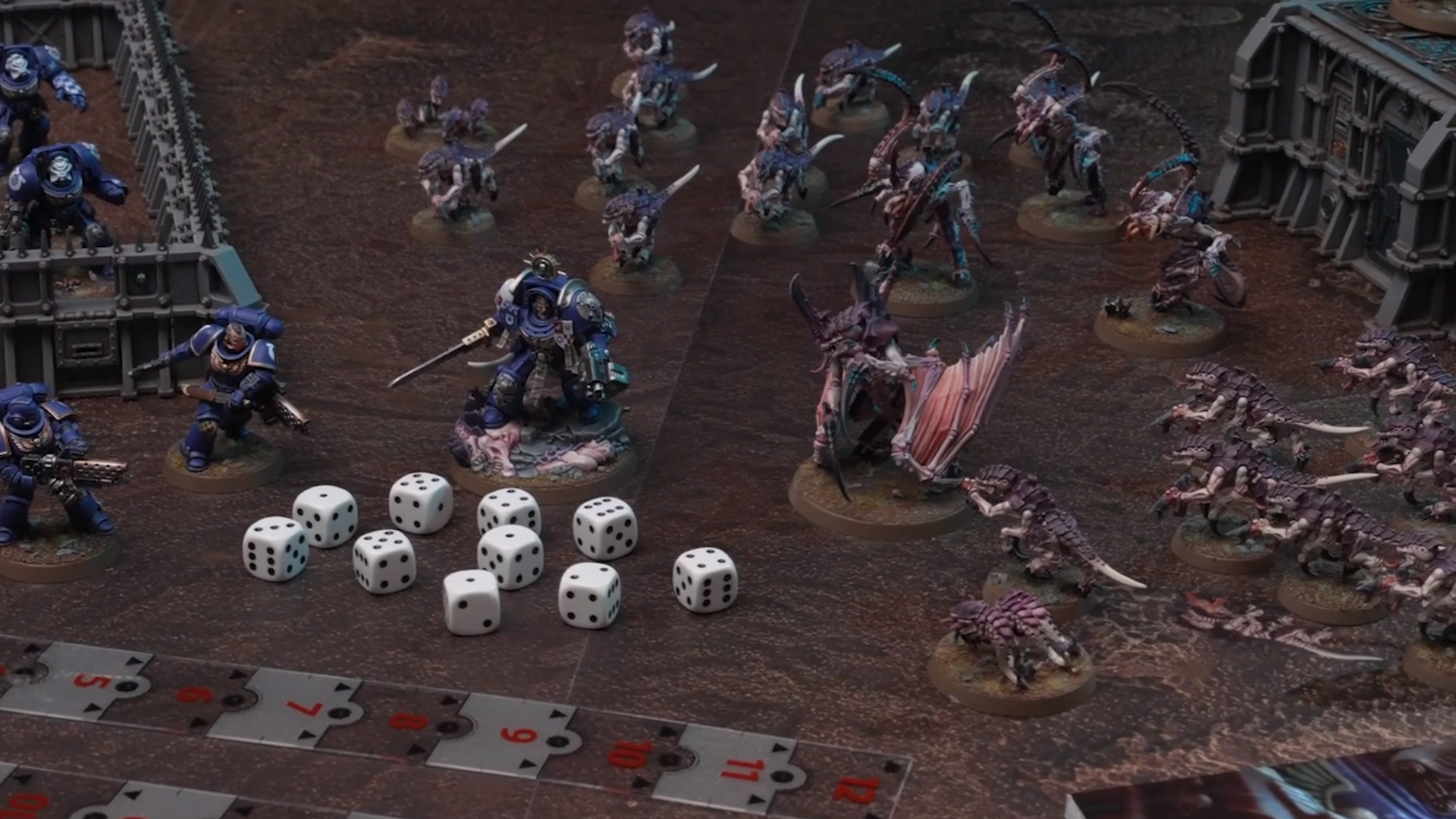 Les troupes des starter sets de Warhammer 40,000 s'affrontent sur un champ de bataille en carton