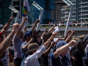 Des travailleurs portuaires en grève de l'International Longshore and Warehouse Union Canada lèvent le poing lors d'un rassemblement à Vancouver, le dimanche 9 juillet 2023.