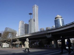 Un habitant traverse une rue calme près de la ligne d'horizon du quartier central des affaires à Pékin, le mardi 13 décembre 2022.