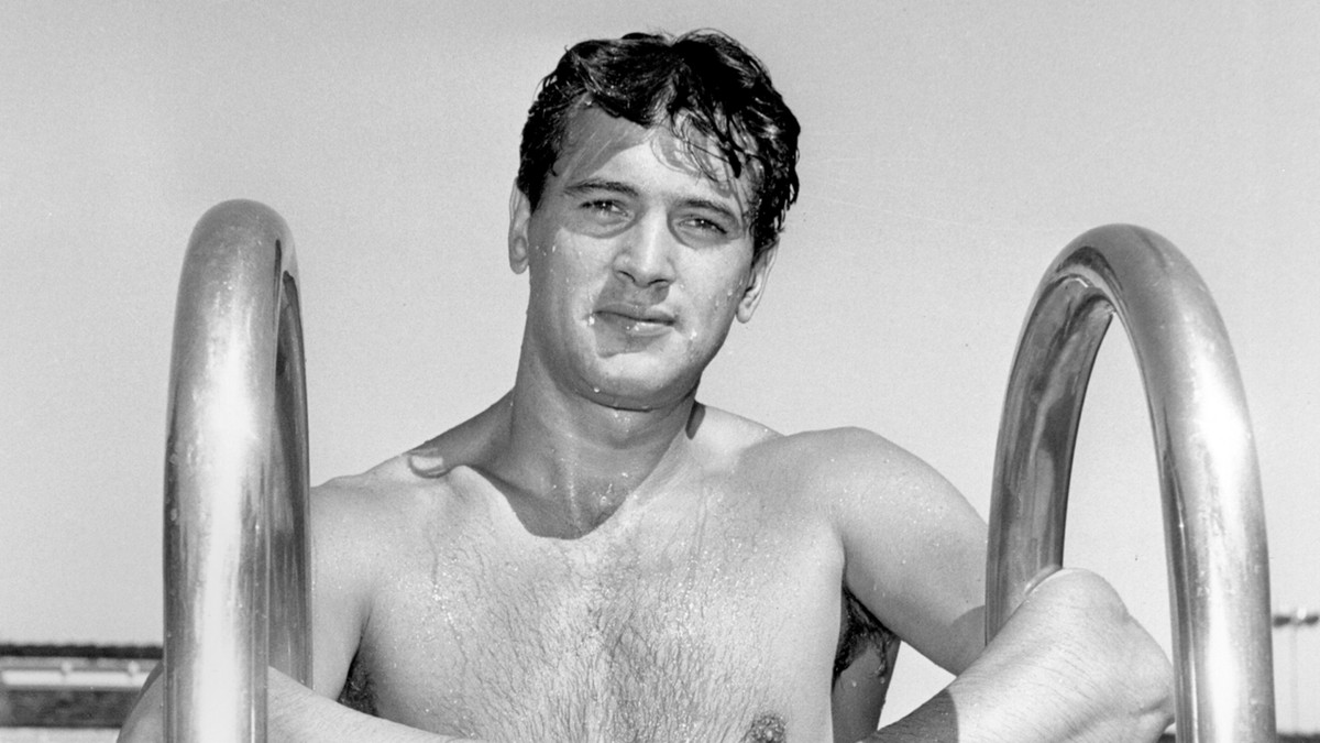 Une photo d'archive en noir et blanc de Rock Hudson au sommet d'une échelle de piscine.