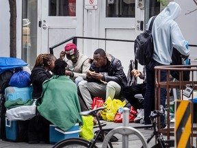 Des demandeurs d'asile sont assis devant un centre d'évaluation et d'orientation pour les sans-abri de la ville de Toronto.