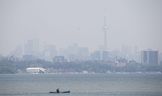 Une personne en canoë va pagayer sur le lac Ontario alors que la fumée obscurcit en partie l'horizon de Toronto au parc Humber Bay Shores le mercredi 7 juin 2023.