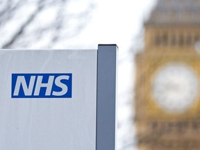 Un panneau NHS est photographié à l'hôpital St Thomas devant le cadran de l'horloge Big Ben et la tour Elizabeth le 13 janvier 2017 à Londres.