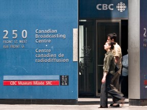 Des piétons marchent devant l'édifice de la CBC au centre-ville de Toronto.