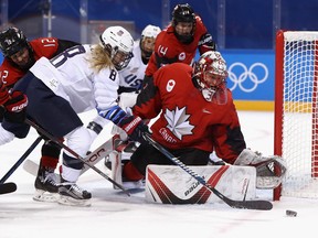 La gardienne de but Geneviève Lacasse cherche à protéger la rondelle au filet contre Emily Pfalzer, membre de l'Association des joueuses professionnelles de hockey féminin, lors des Jeux olympiques d'hiver de PyeongChang 2018 à Gangneung, en Corée du Sud.