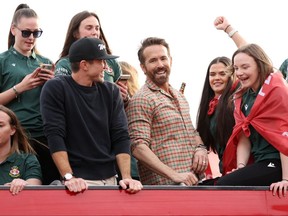 Les copropriétaires de Wrexham Ryan Reynolds et Rob McElhenney célèbrent avec les joueurs lors d'un défilé de bus.