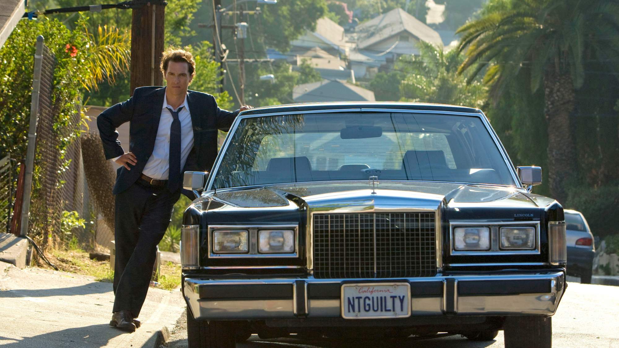 Matthew McConaughey s'appuie sur une voiture dans le film The Lincoln Lawyer