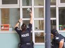 Officier médico-légal de la police de Toronto Det.-Const.  Rhonda Haley prend des images d'une balle qui a percé une fenêtre dans une garderie à la suite d'une fusillade en voiture.