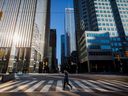 Une femme traverse la rue pendant les heures de trajet du matin dans le quartier financier de Toronto.