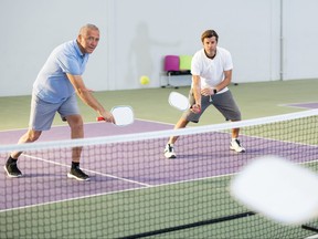 Deux hommes d'âges différents jouant à un jeu de pickleball