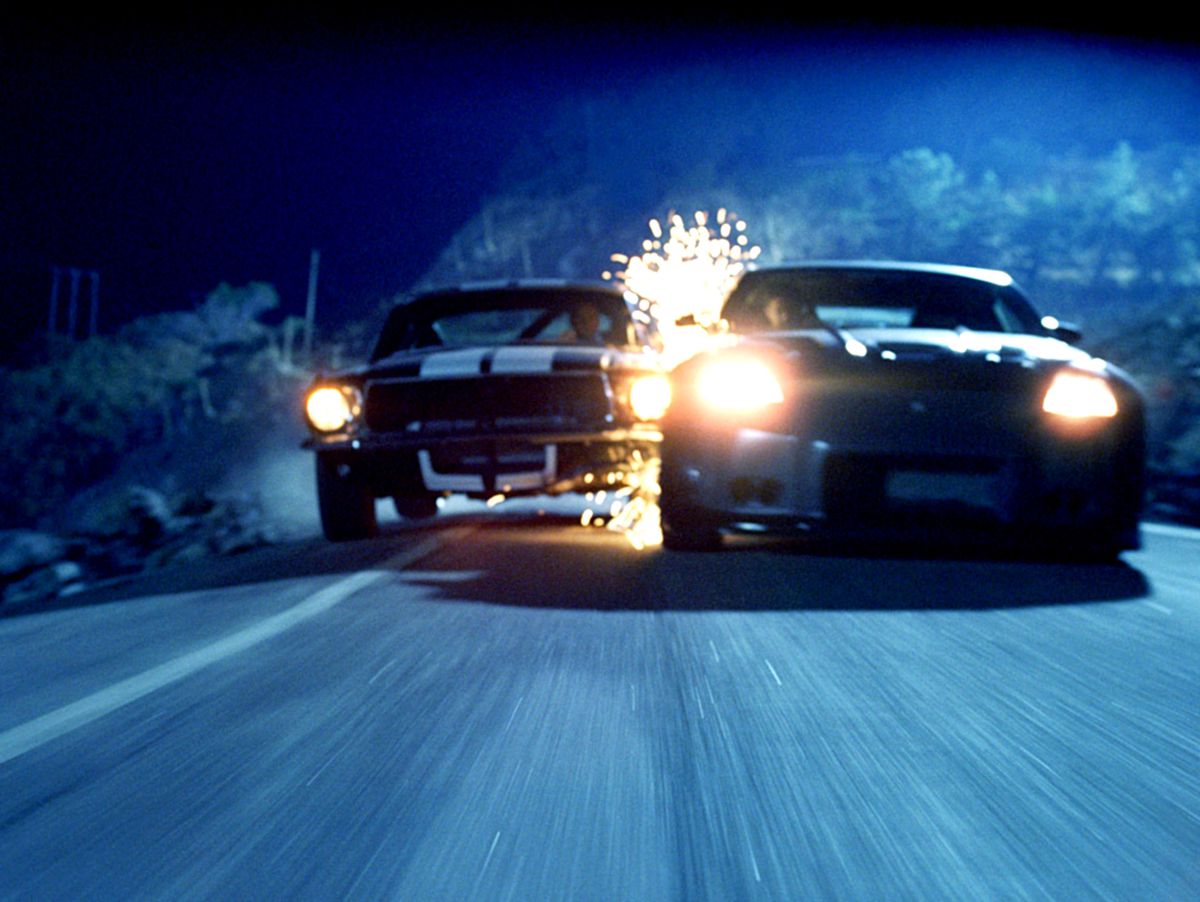 Des étincelles volent alors que deux muscle cars entrent en collision alors qu'ils dérivent sur une route étroite dans The Fast and the Furious : Tokyo Drift.