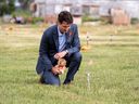 Le premier ministre Justin Trudeau dépose un ours en peluche sur un petit drapeau dans un champ avant une cérémonie sur le site d'un ancien pensionnat de la Première Nation de Cowessess, en Saskatchewan, le 6 juillet 2021.