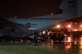 Certaines des dernières personnes à avoir évacué Yellowknife descendent d'un avion militaire canadien C-130 Hercules, le 19 août 2023, à l'aéroport international d'Edmonton.