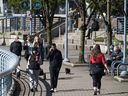 Piétons et coureurs à la digue de Yaletown lors d'une journée ensoleillée à Vancouver.