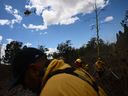 Un hélicoptère de lutte contre les incendies largue des fournitures alors que les pompiers du comté de Maui éteignent un incendie près des maisons lors des incendies de forêt dans l'arrière-pays de Maui, à Kula, à Hawaï, le 13 août 2023.  