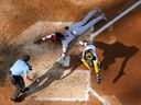 Elly De la Cruz des Cincinnati Reds vole la maison avec le receveur des Milwaukee Brewers William Contreras couvrant la septième manche d'un match de baseball le samedi 8 juillet 2023, à Milwaukee.