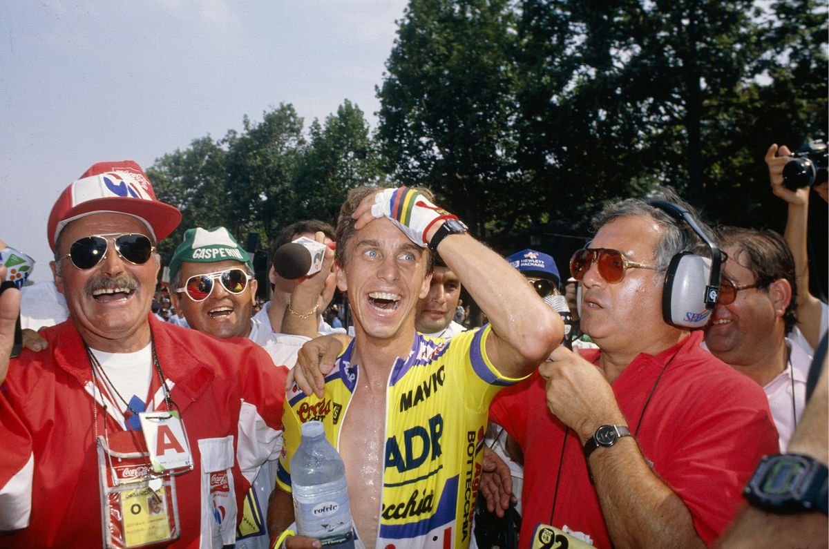 Greg LeMond tient sa main sur son visage avec incrédulité alors qu'il est félicité après une victoire miraculeuse du Tour de France.