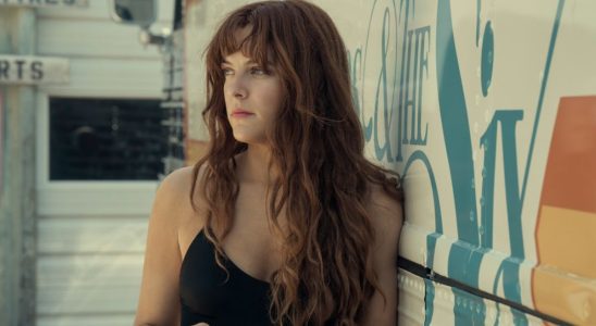 Riley Keough in Daisy Jones and the Six leaning against a tour bus