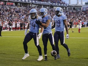 Le porteur de ballon des Argonauts de Toronto AJ Ouellette (34 ans) célèbre son touché contre les Redblacks d'Ottawa avec ses coéquipiers le receveur large David Ungerer III (83 ans) et le receveur large Kurleigh Gittens Jr. (19 ans) lors de la première mi-temps de l'action de football de la LCF à Toronto, le dimanche 13 août. , 2023.