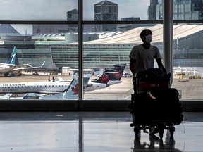 Un voyageur marchant avec ses bagages à l'aéroport international Pearson de Toronto.