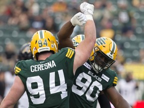 Les joueurs de ligne défensive des Elks d'Edmonton Kony Ealy (90) et Jake Ceresna (94) célèbrent un sac du quart-arrière contre les Tiger-Cats de Hamilton au Commonwealth Stadium d'Edmonton le 13 juillet 2023.