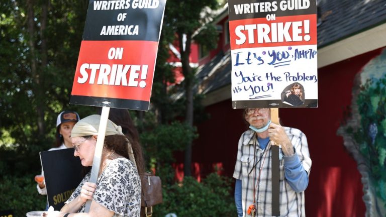 BURBANK, CALIFORNIA - JULY 17: People hold signs in support of striking WGA (Writers Guild of America) members on Day 5 outside Warner Bros. Studio on July 17, 2023 in Burbank, California. Members of SAG-AFTRA, Hollywood’s largest union which represents actors and other media professionals, have joined the striking writers in the first joint walkout against the studios since 1960. The strike could shut down Hollywood productions completely with writers in the third month of their strike against the Hollywood studios. (Photo by Mario Tama/Getty Images)