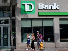 Des gens passent devant une banque Toronto-Dominion à Miami Beach, en Floride.