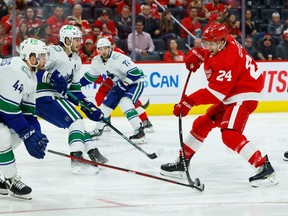 Le centre des Red Wings de Détroit Pius Suter (24 ans) tire la rondelle contre le défenseur des Canucks de Vancouver Kyle Burroughs (44 ans) en deuxième période au Little Caesars Arena.  Rick Osentoski - USA TODAY Sports