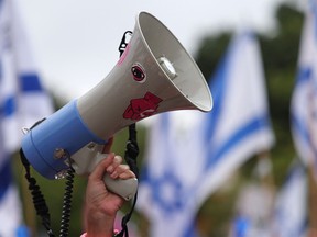 Un manifestant utilise un mégaphone pour scander des slogans lors d'un rassemblement contre le plan de refonte judiciaire du gouvernement israélien à Tel Aviv le 12 août 2023.