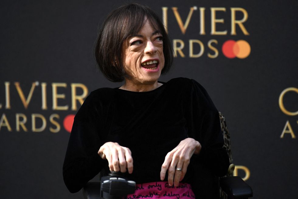 Liz Carr portant un haut noir et une jupe magenta sur le tapis rouge