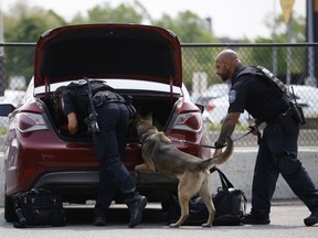 Les agents des douanes et de la protection des frontières des États-Unis fouillent des véhicules avec l'aide d'un chien au port d'entrée du Peace Bridge à Buffalo, NY, le mardi 23 mai 2023. Plus tôt cette année, les agents frontaliers américains ont utilisé des hélicoptères et un avion à voilure fixe pour arrondir 124 personnes le long de la frontière canado-américaine.