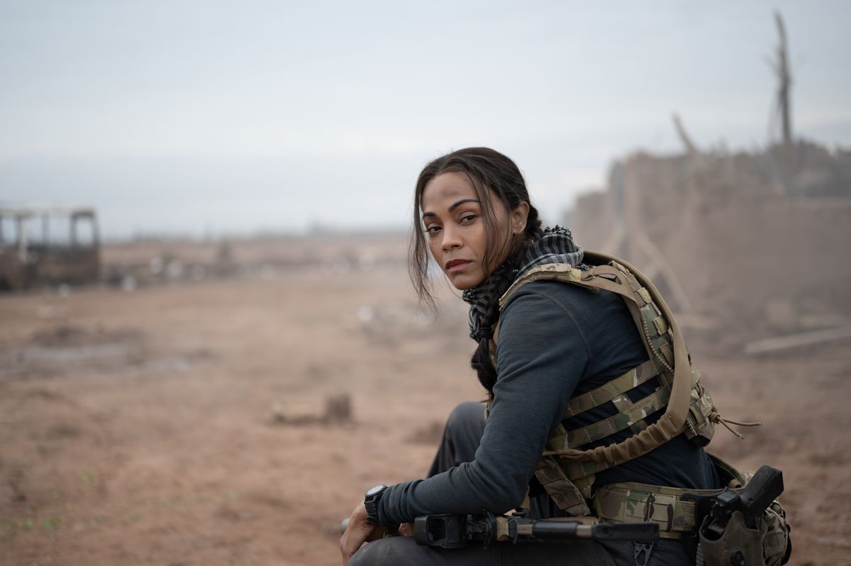 Zoe Saldaña est assise en tenue de combat complète au bord d'un champ de bataille dans la série Paramount Plus Special Ops: Lioness