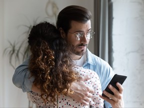 Mari jaloux étreignant sa femme et vérifiant son téléphone