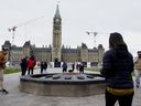 Les visiteurs et les touristes de la Colline du Parlement se tiennent autour de la flamme du centenaire sur la Colline du Parlement à Ottawa, le vendredi 22 octobre 2021. La Chine a levé l'interdiction liée à la pandémie sur les voyages de groupe dans plusieurs pays, dont les États-Unis et l'Australie, mais les touristes sont toujours interdits. de visites de groupe au Canada.