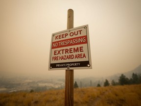 La bataille désespérée de la Colombie-Britannique contre des centaines d'incendies de forêt se poursuit dimanche sur plusieurs fronts.  Un panneau d'avertissement sur le risque d'incendie est visible alors que la fumée des incendies de forêt remplit l'air, à Kelowna, en Colombie-Britannique, le samedi 19 août 2023.