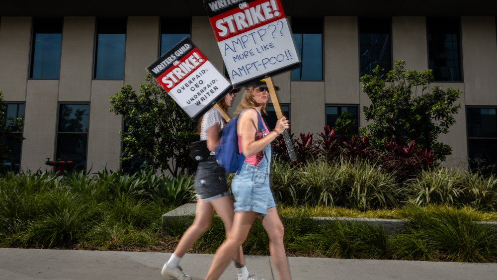 Hollywood, CA - July 31: Someone carried a sign that asked, "AMPTP?? More Like AMPTP-POO!!," while joining members of the Writers Guild of America (WGA),  members of the Screen Actors Guild (SAG) and American Federation of Television and Radio Artists (AFTRA), to picket in front of Netflix headquarters, in Hollywood, CA, Monday, July 31, 2023. Entertainment's largest guilds have come together, during disputed contract negotiations with the Alliance of Motion Picture and Television Producers (AMPTP).(Jay L. Clendenin / Los Angeles Times via Getty Images)