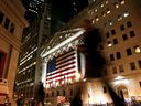 Les piétons passent la nuit devant la Bourse de New York, dans le centre-ville de Manhattan, à New York.