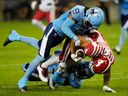 Le demi défensif des Argonauts de Toronto Royce Metchie (9) et le secondeur Jordan Williams (en bas) affrontent le receveur large des Stampeders de Calgary Reggie Begelton (84) lors de la première mi-temps de football de la LCF à Toronto, le vendredi 25 août 2023.