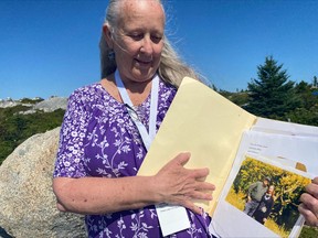 Claire Mortimer pose avec une photo d'elle et de son père, John Mortimer, décédé dans l'accident du vol Swissair 111 en septembre 1998, au mémorial Peggy's Cove Swissair à Indian Harbour, en Nouvelle-Écosse, le dimanche 3 septembre 2023.