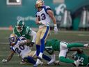 Le porteur de ballon des Blue Bombers de Winnipeg, Brady Oliveira (20 ans), est affronté par la défense des Roughriders de la Saskatchewan pendant la deuxième moitié du match Classique de la fête du Travail opposant les Roughriders de la Saskatchewan aux Blue Bombers de Winnipeg au stade Mosaic, le dimanche 4 septembre 2022 à Regina. 